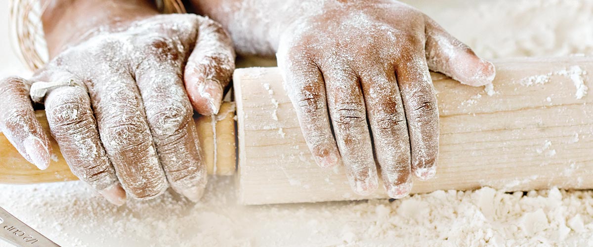 Grandparent and child hands on a rolling pin
