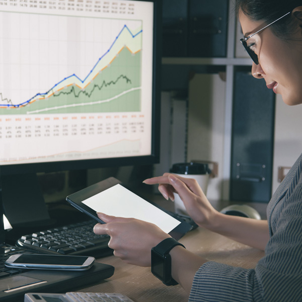 Woman looking at charts on multiple screens