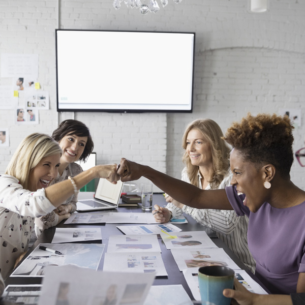 Professional women sharing a fist bump at a conference table