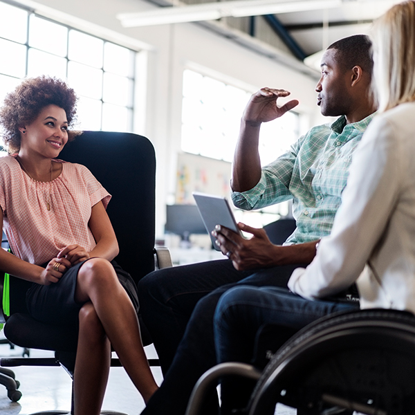 Three employees talking at work. One is in a wheelchair.