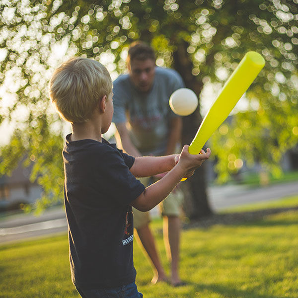 Young boy hitting a baseball to his dad