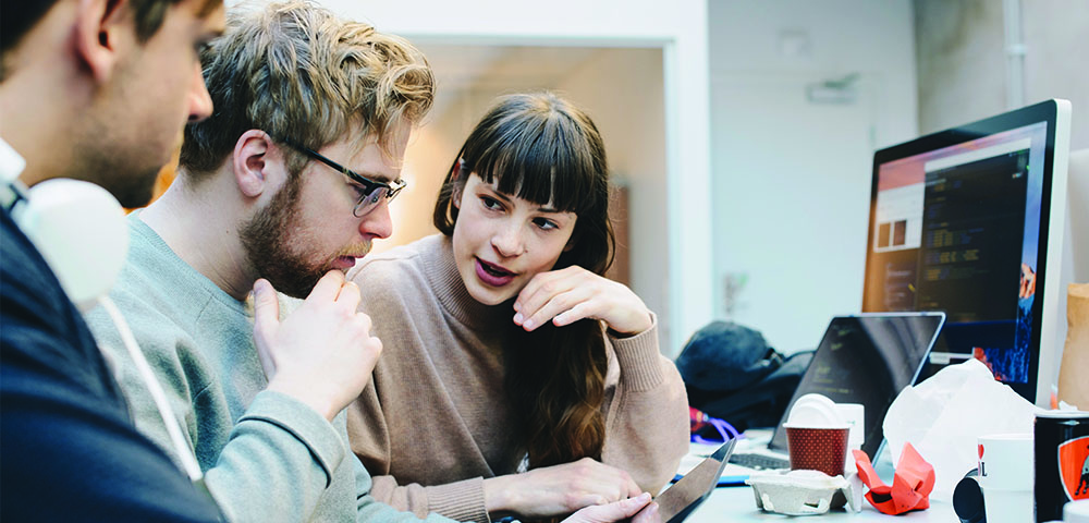 Two men and a woman looking at a tablet