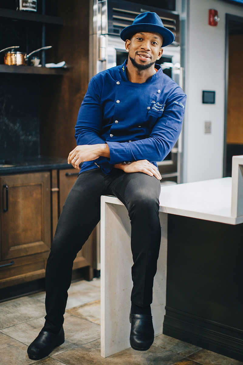 Chef Darian Bryan in a deep blue chef's coat and matching tilby hat