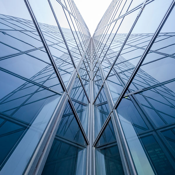 An abstract upward view of a modern glass-clad skyscraper