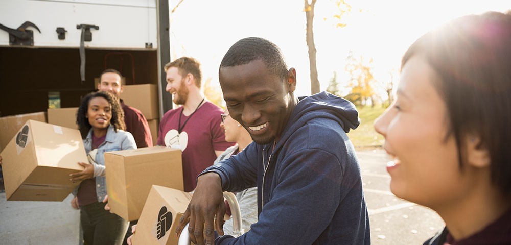 Smiling younger men and women loading boxes onto a truck