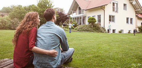Couple looking at house, watching kids play