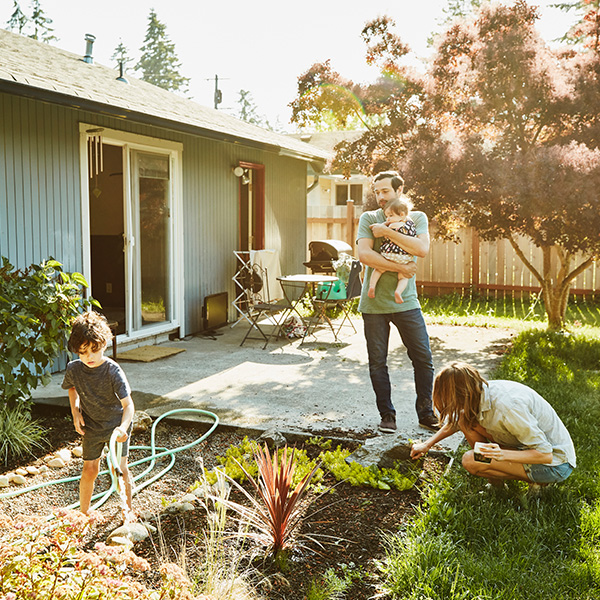 A young family working in the yard outside their home on a sunny day