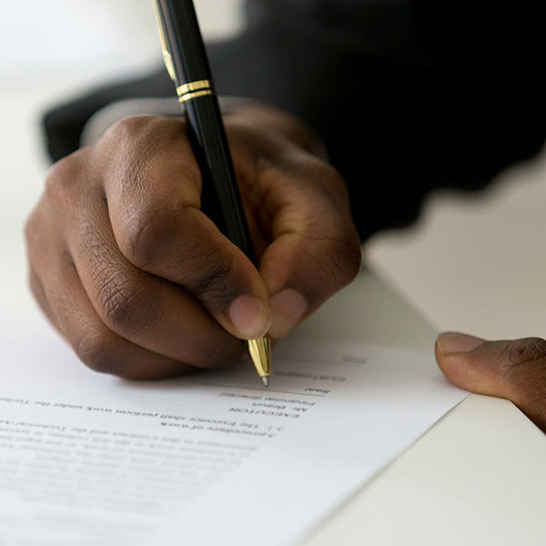 A close view of a man's hands as he signs the bottom of a legal document