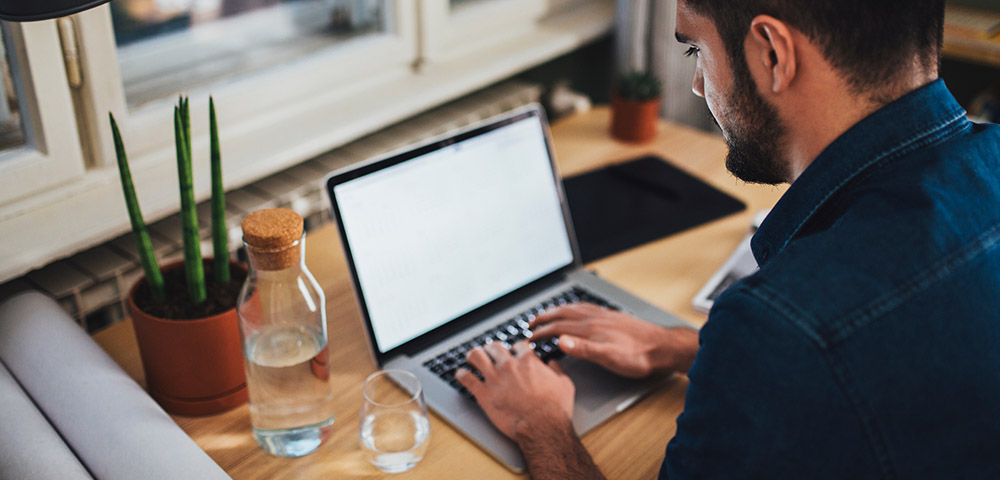 Man sitting at a desk typing on a laptop