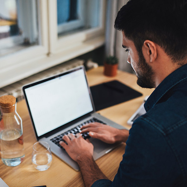 Man sitting at a desk typing on a laptop