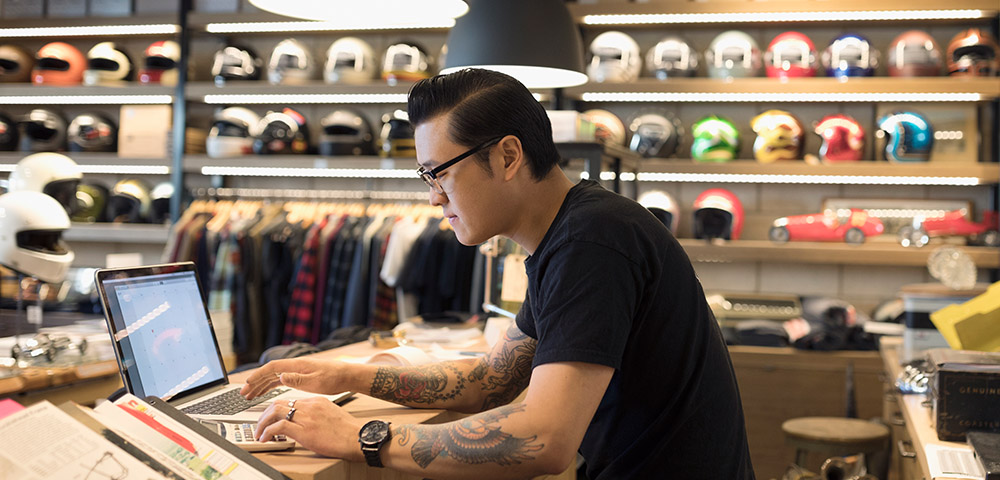 Man working in a store with a laptop and calculator