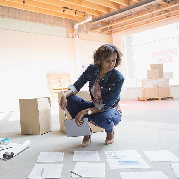 woman crouching on floor looking at documents